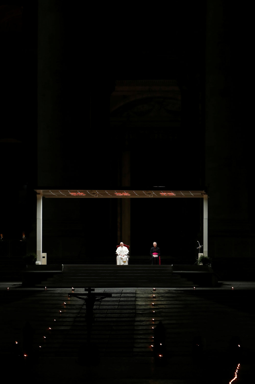 Workers light candles in St. Peter’s Square at the Vatican April 10, 2020, before the Via Crucis procession led by Pope Francis. The Good Friday service was held with no public participation because of the COVID-19 pandemic.